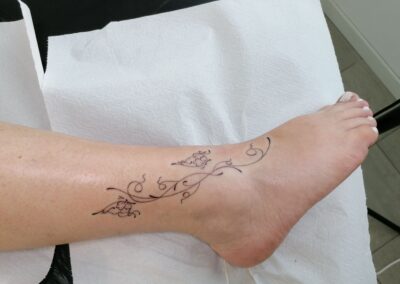 Tattoo fine line floreale sulla caviglia realizzato da Giorgia Arzenton