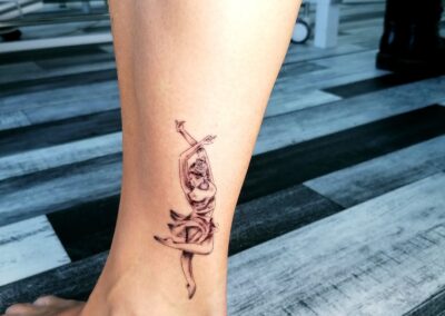 Tatuaggio fine line con figura di danzatrice sulla caviglia realizzato ad Aurea Studio