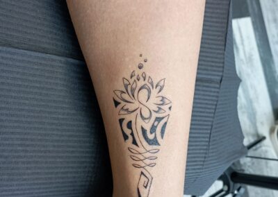 Tatuaggio fine line con fiore di loto geometrico sulla caviglia realizzato ad Aurea Studio